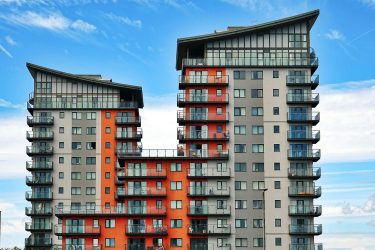 Modern high-rise apartment buildings with unique architecture under a vibrant blue sky.